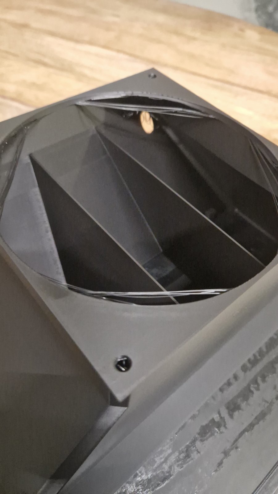 Conducto impreso con hebras de filamento en las esquinas de la brida del ventilador